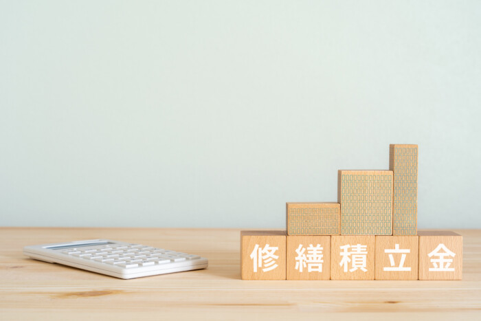 修繕積立金と書かれたブロックとマンションのミニチュアと電卓